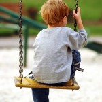 shutterstock_2232615 lonely boy in park on swing