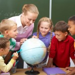 teacher looking at globe with children