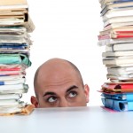 man staring at piles of paper