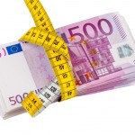 Measuring tape wrapped around a wad of Euros