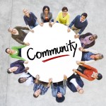 Group of people holding a circle with the word community on it