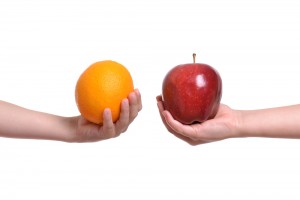 One hand holding an orange, the other holding an apple