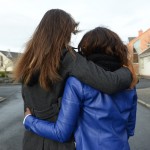 A young woman suffering from depression is consoled by her friend.