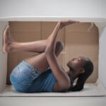 Young african woman stuck in a carton