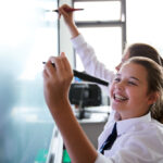 Female,High,School,Students,Wearing,Uniform,Using,Interactive,Whiteboard,During
