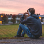 Upset,Teenager,Sitting,On,The,Ground,All,Alone,While,Listening