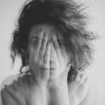 Double exposure black and white portrait of a woman covering her face and eyes with her hands