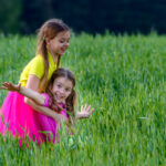 Two,Little,Girls,Playing,On,The,Green,Grass.