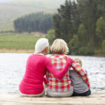 Mother,,Daughter,And,Grandmother,Sitting,On,A,Jetty