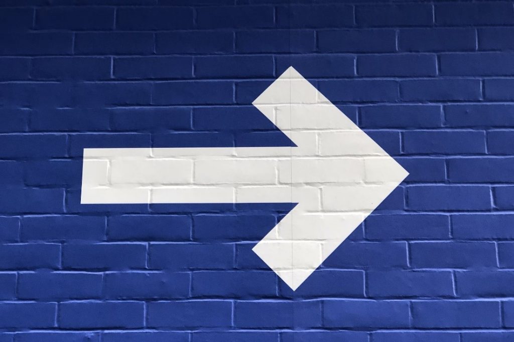 Big white arrow on a blue bricked wall