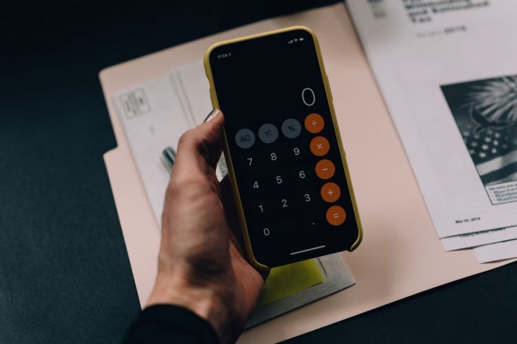 a hand holding an iphone which has the calculator open on zero