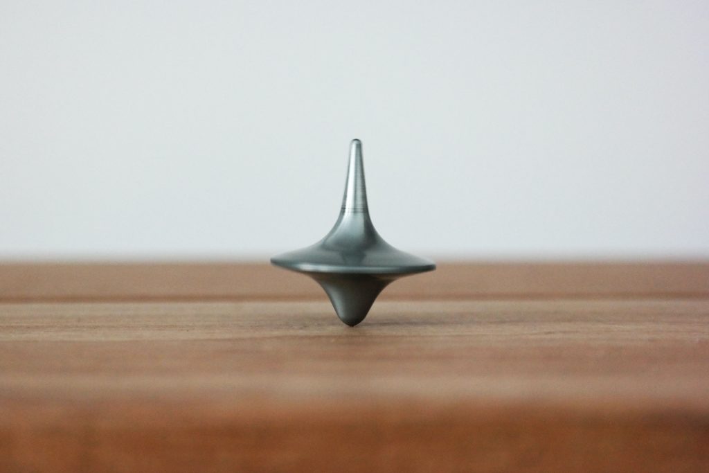 A grey spinning top on a brown table
