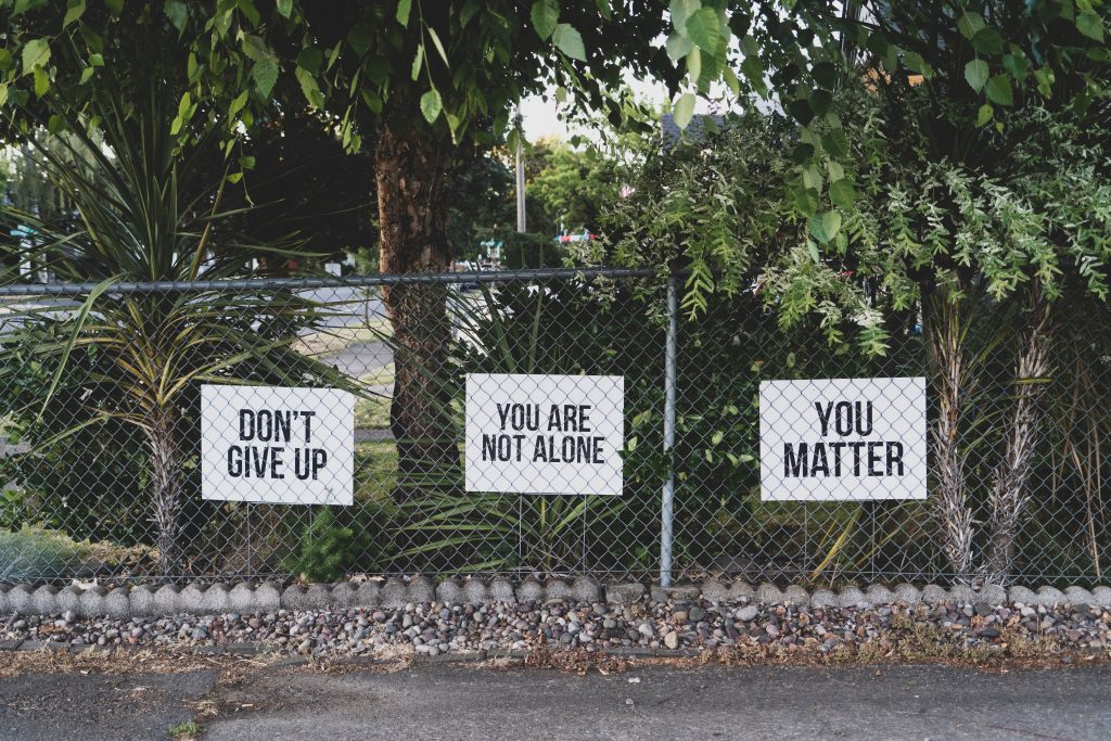 Three signs are attached to wire railings that read 'don't give up', 'you are not alone' and 'you matter'