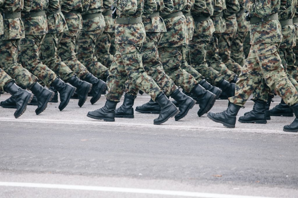 soldiers in khaki camouflage uniforms march together perfectly in line