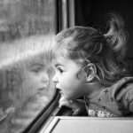 Cute little girl staring through window on a train journey