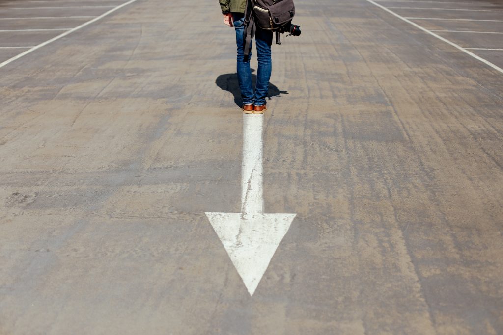 a white arrow pointing towards the camera, there's a person standing on the start of the arrow.