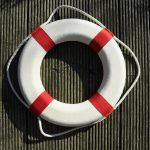 a red and white life buoy on a wooden floor
