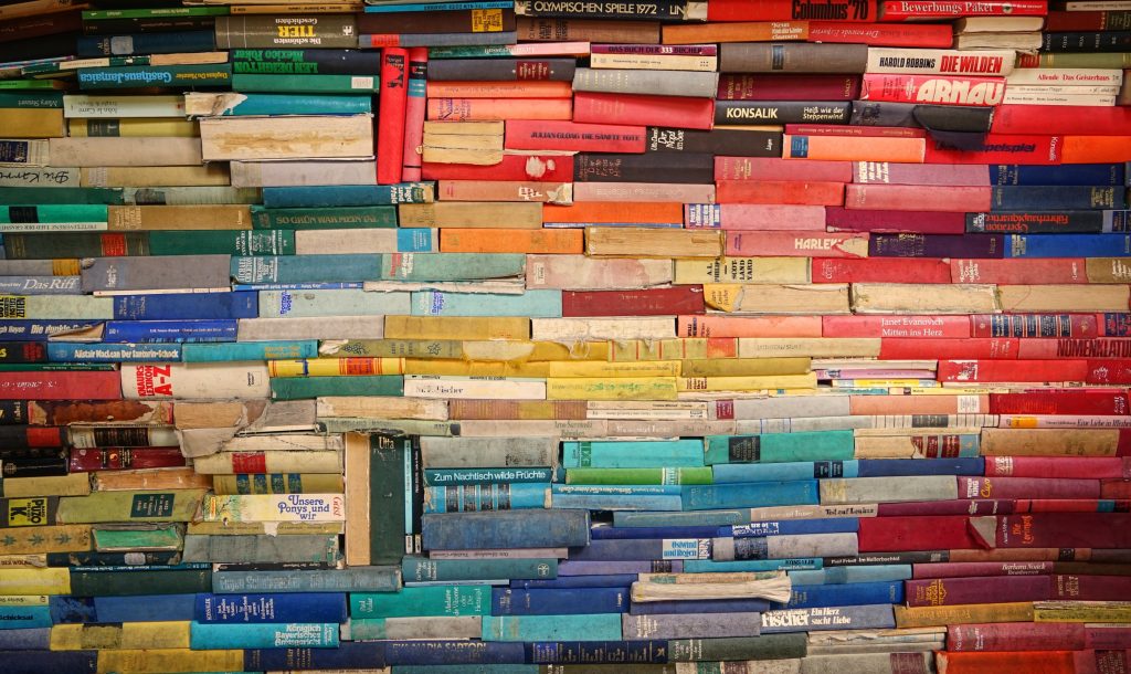 picture is full of books stacked together with all different colour binds