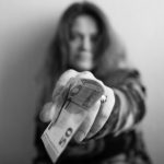 A,Woman,Holds,Out,Her,Hand,And,Holds,A,Banknote