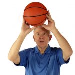 A senior man preparing a two-handed basketball shoot.  Isolated on white.