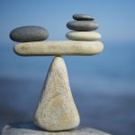 Balance of stones. To weight pros and cons. Balancing stones on the top of boulder. Close up. Balance of stones on a blue sky background with a copy space. Scales. Stones balance, sustainability.