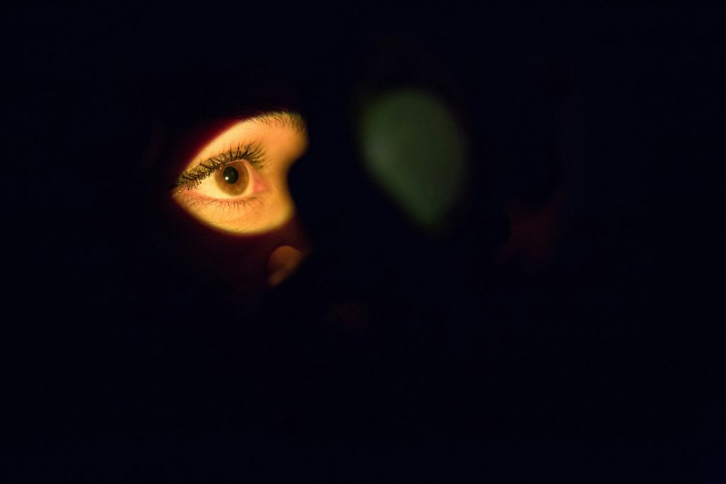 An eye is highlighted in light surrounded by darkness
