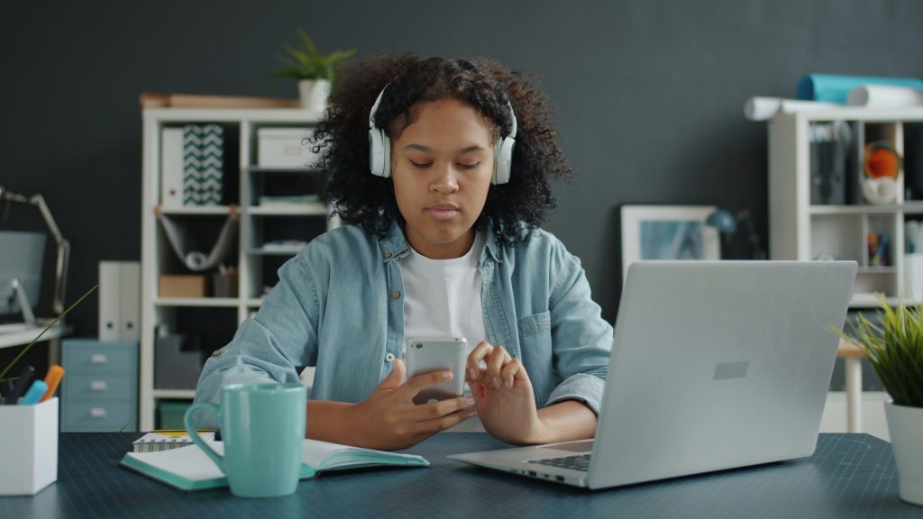 A young person with headphones on looking at their phone