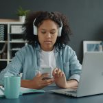 A young person with headphones on looking at their phone