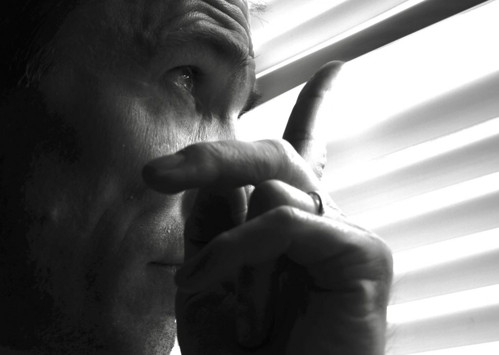 Person looks through a blind