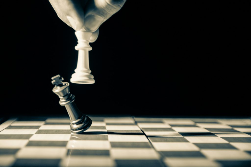 A black chess piece being knocked over with a white one