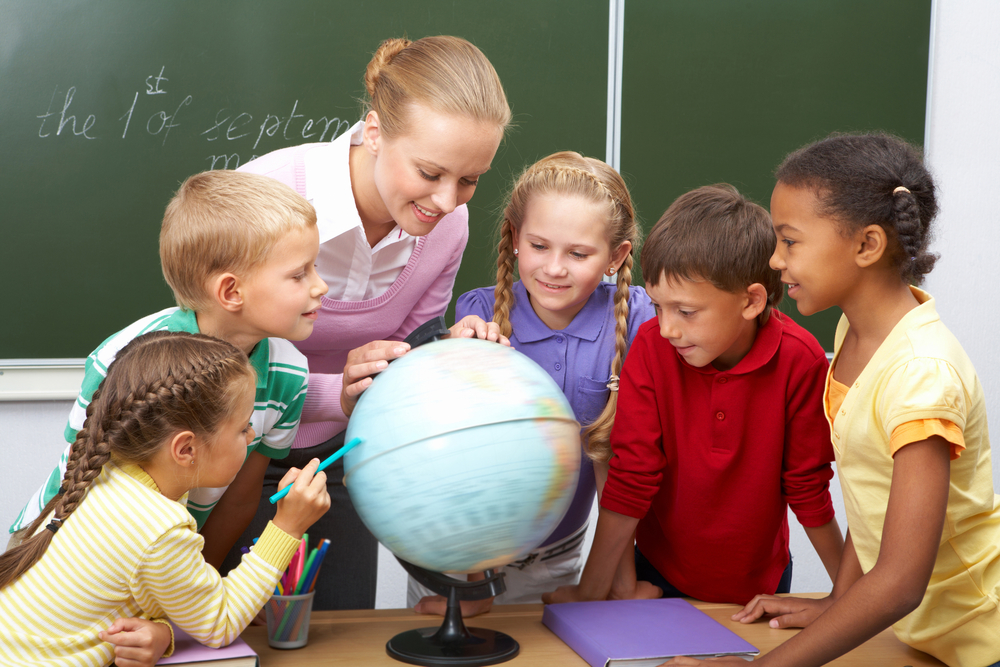 teacher looking at globe with children