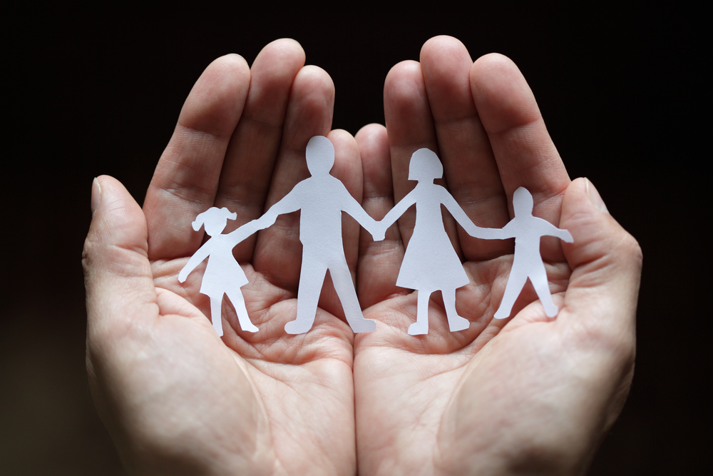 Hands holding paper cut-outs of people