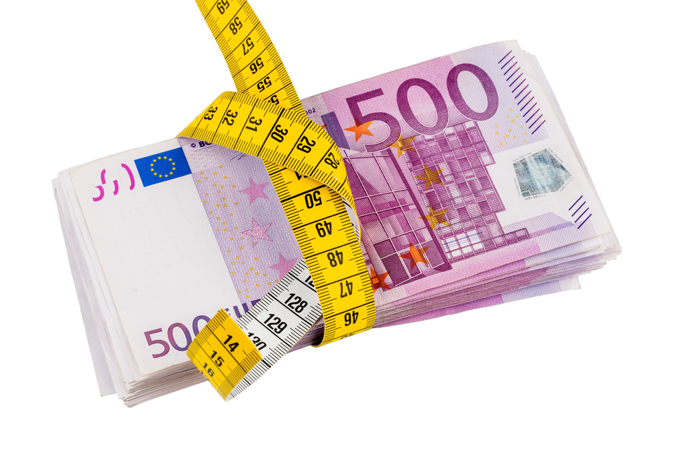 Measuring tape wrapped around a wad of Euros