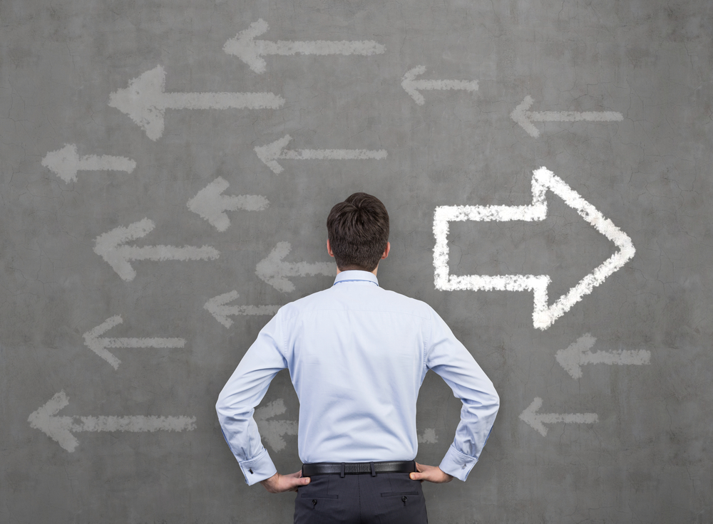 Man looking at blackboard with arrows pointing mainly in one direction