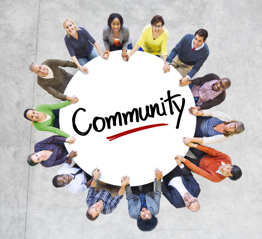 Group of people holding a circle with the word community on it