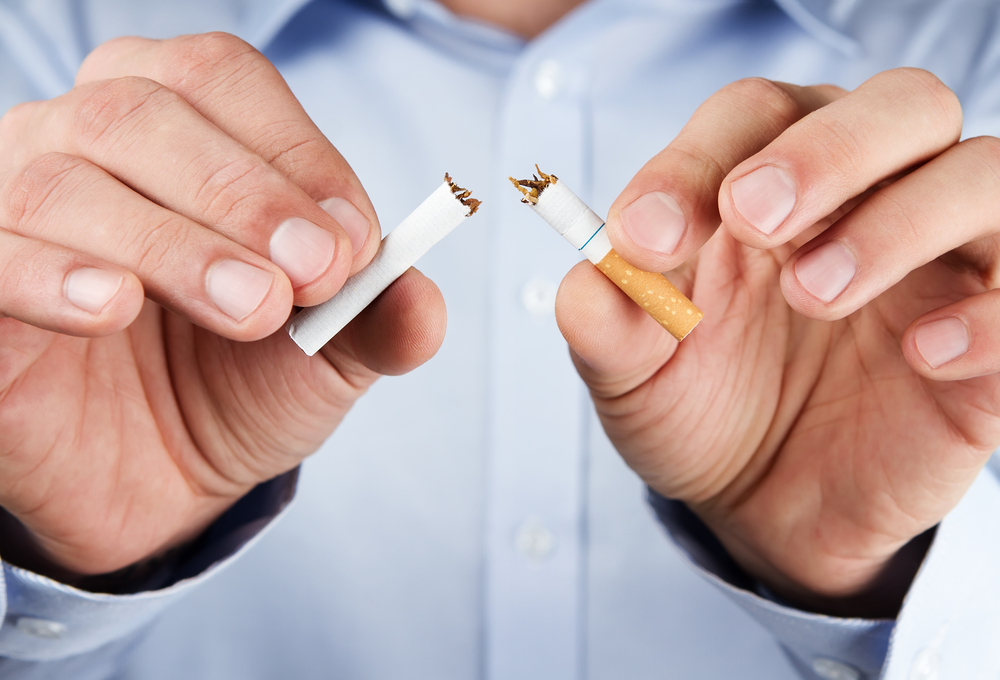 Person breaking a cigarette in half