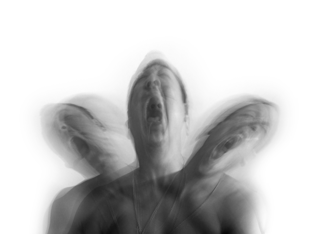 Blurry black and white picture of three heads screaming