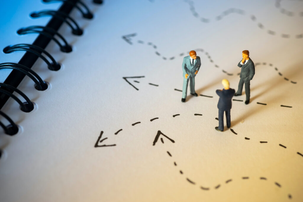 Business illustration of three suited businessmen standing on a notebook with dotted lines and arrows pointing in different directions