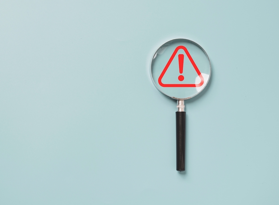 Magnifying glass highlighting a red exclamation mark