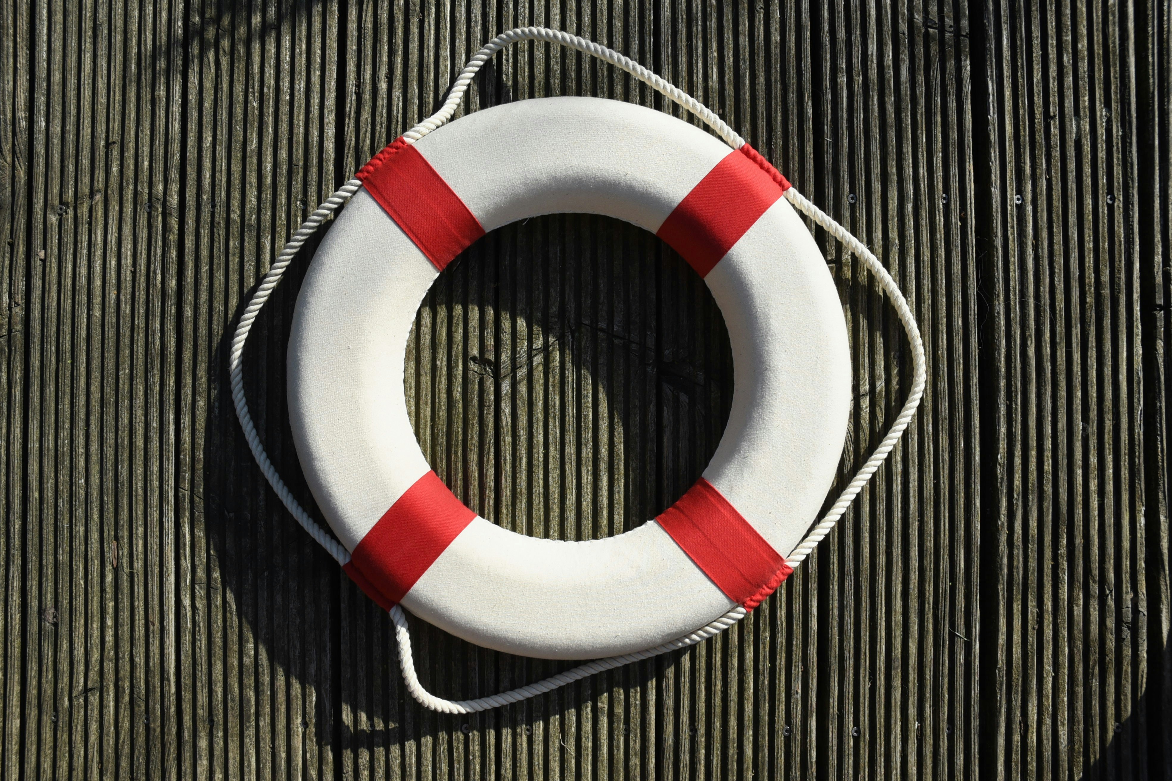 a red and white life buoy on a wooden floor