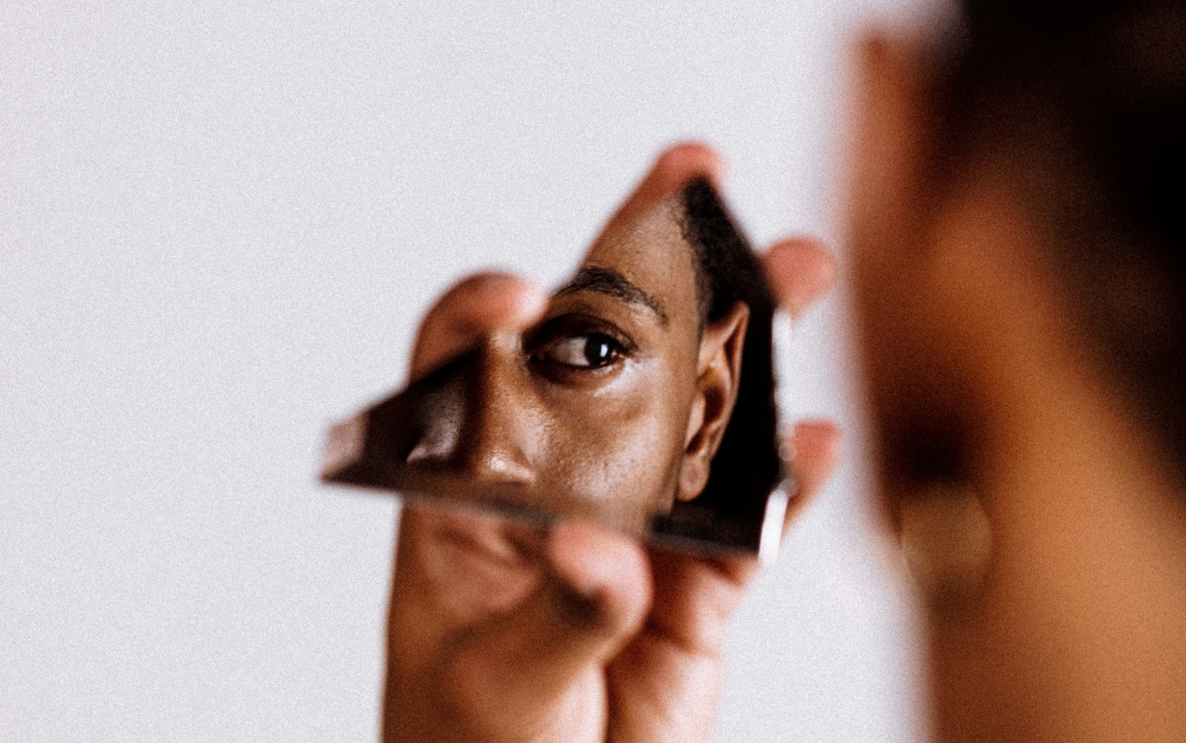 Someone looking into a piece of broken mirror.