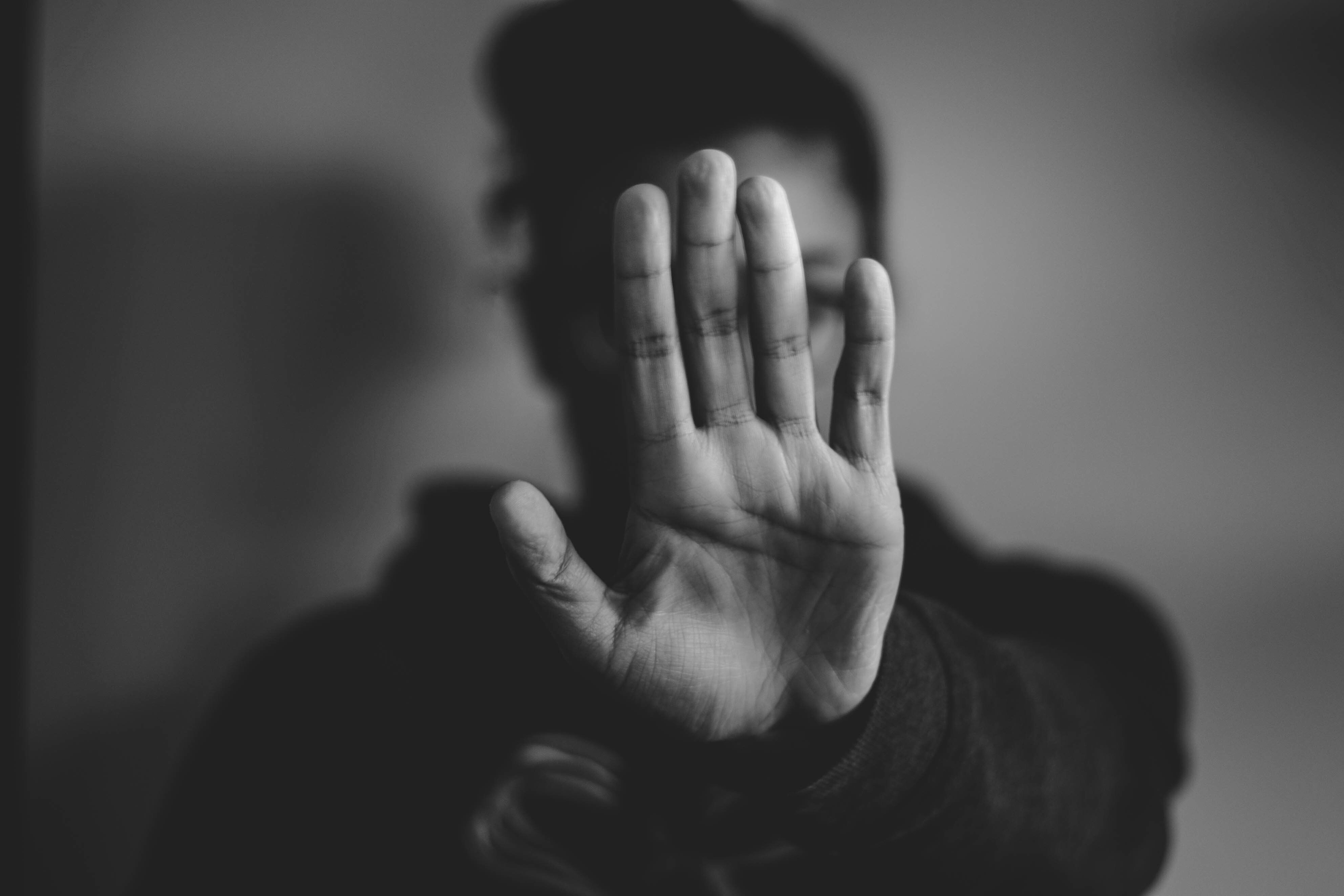Someone holding up their hand to obscure the view of their face.