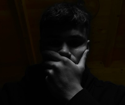 Person in dark light with a hand over their mouth