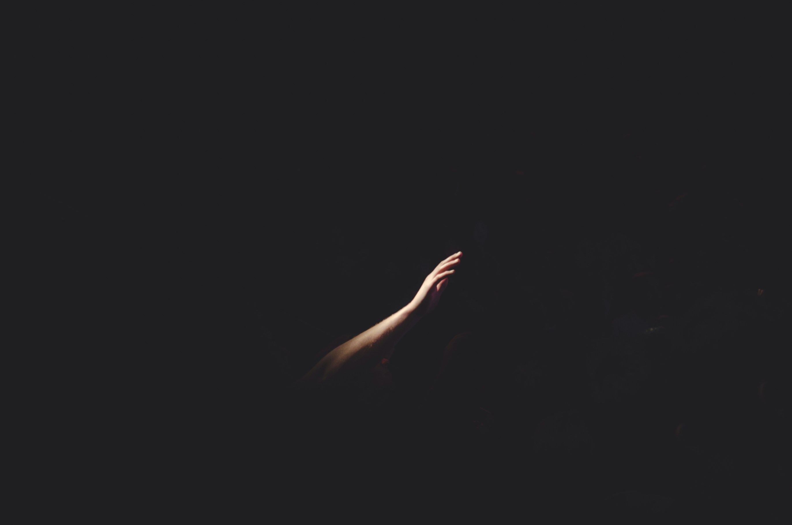 A hand and arm reach out from darkness