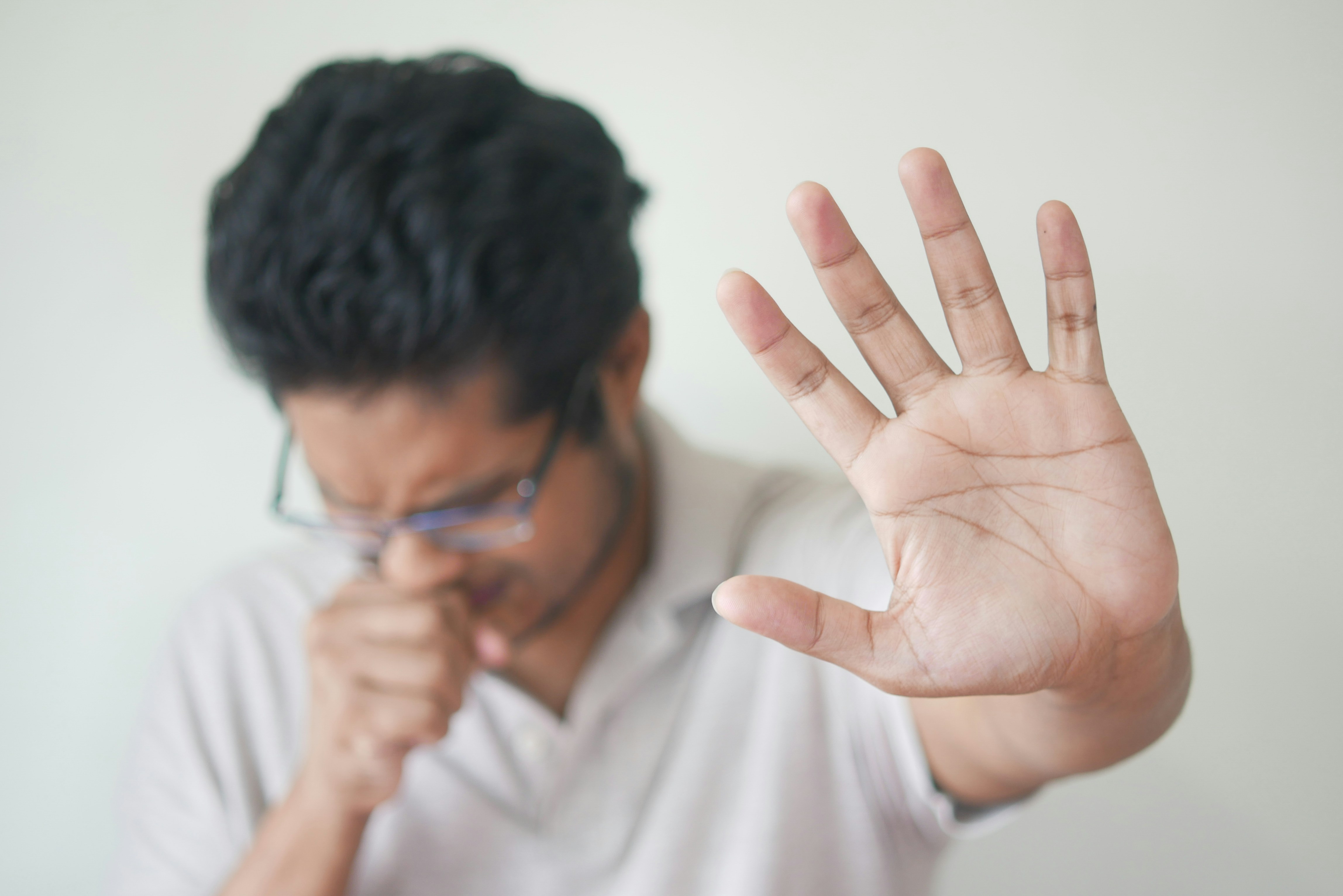 Someone coughing and holding there hand up to ward off people