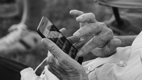 An older person holding a phone with only their hands visible