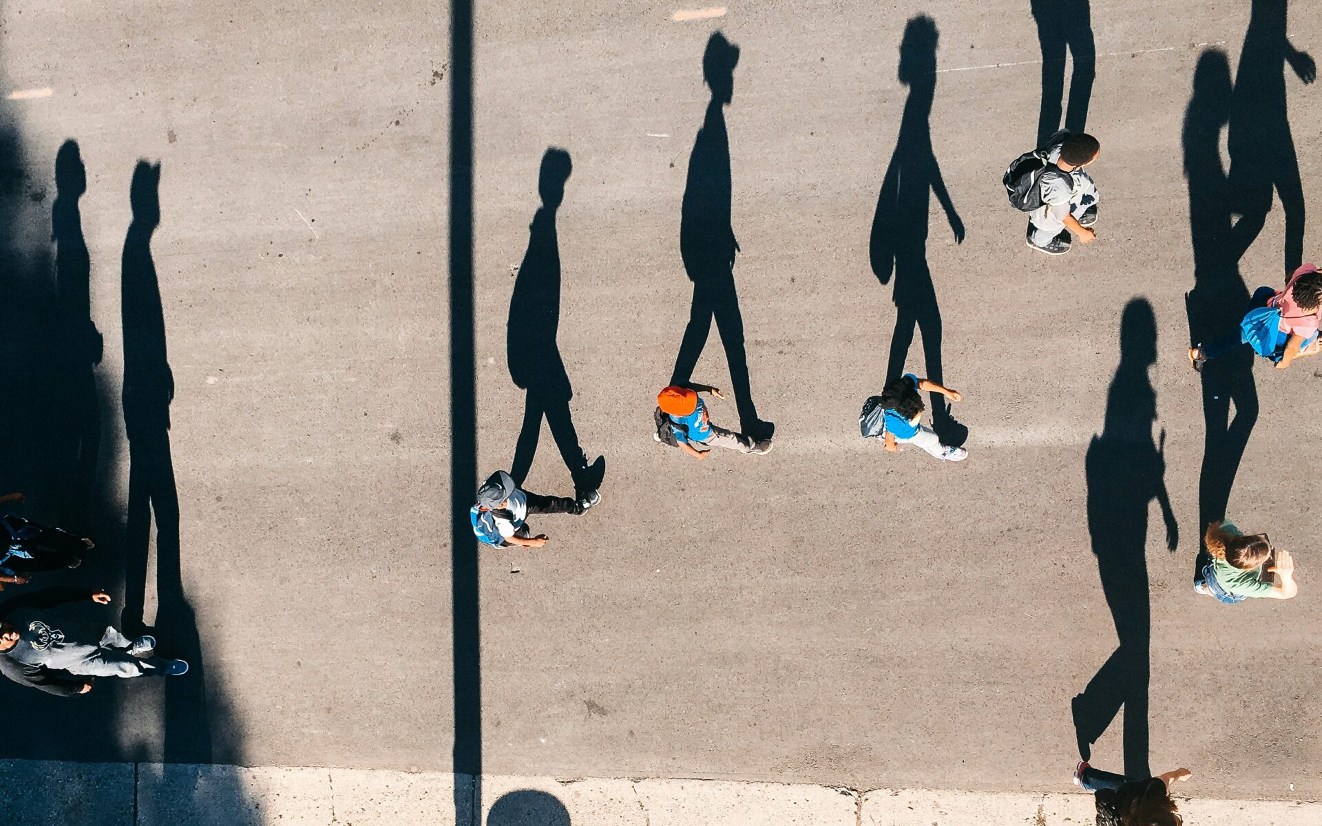 People walking on a street pictured from above with long shadows