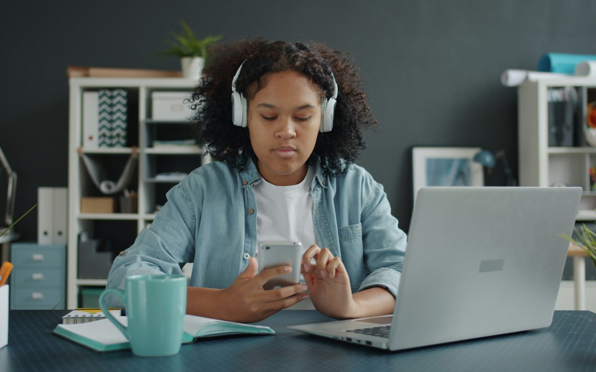 A young person with headphones on looking at their phone