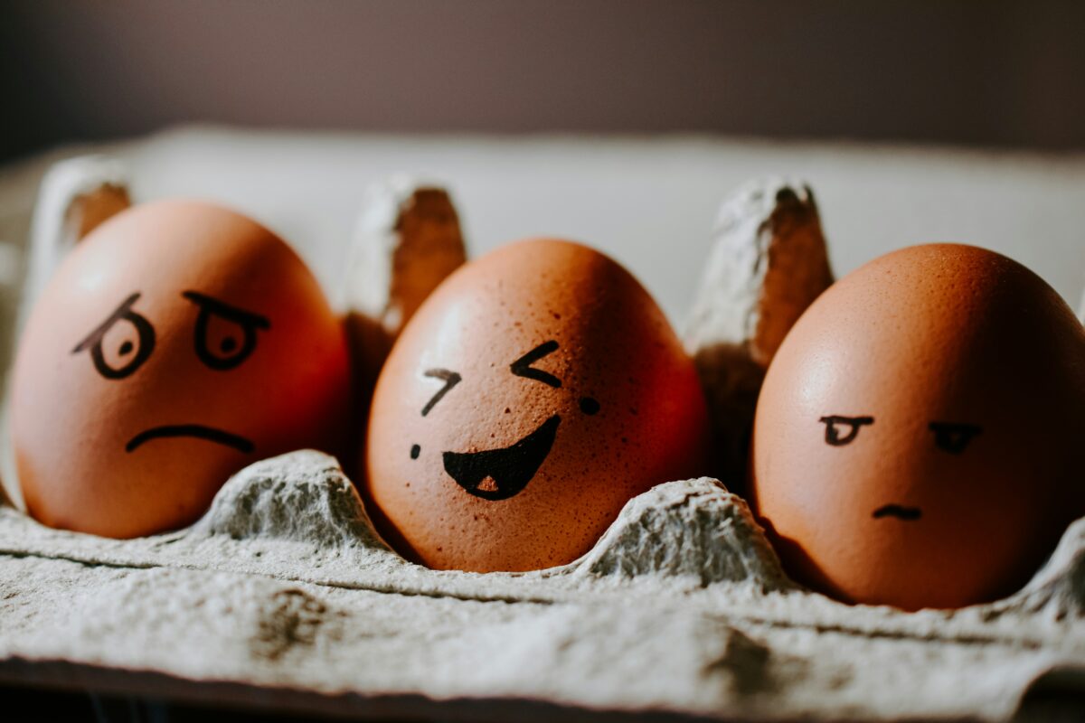 Brown eggs in egg carton with varying emotional expressions