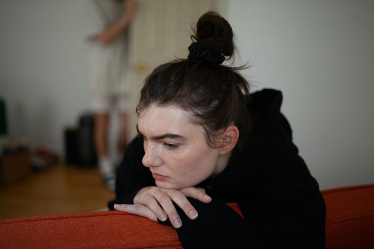 A woman has her head on her hands on a red couch